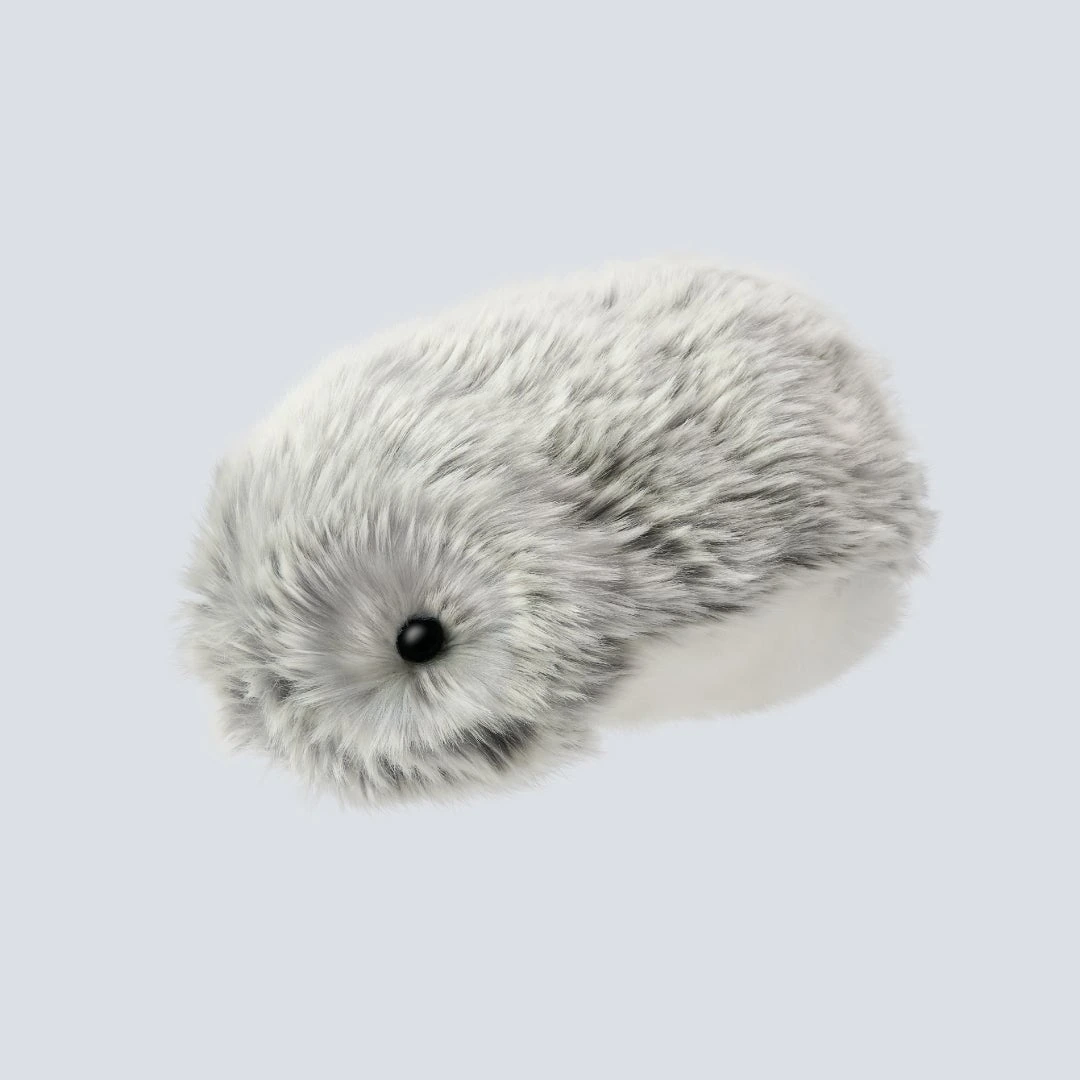 The silver Moflin robotic pet with its small head nestled in soft grey fur.