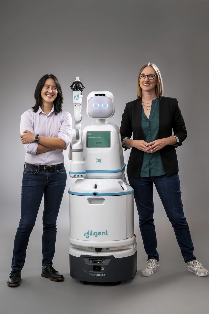 Diligent Robotics founders Vivian Chu and Andrea Thomaz standing beside Moxi.