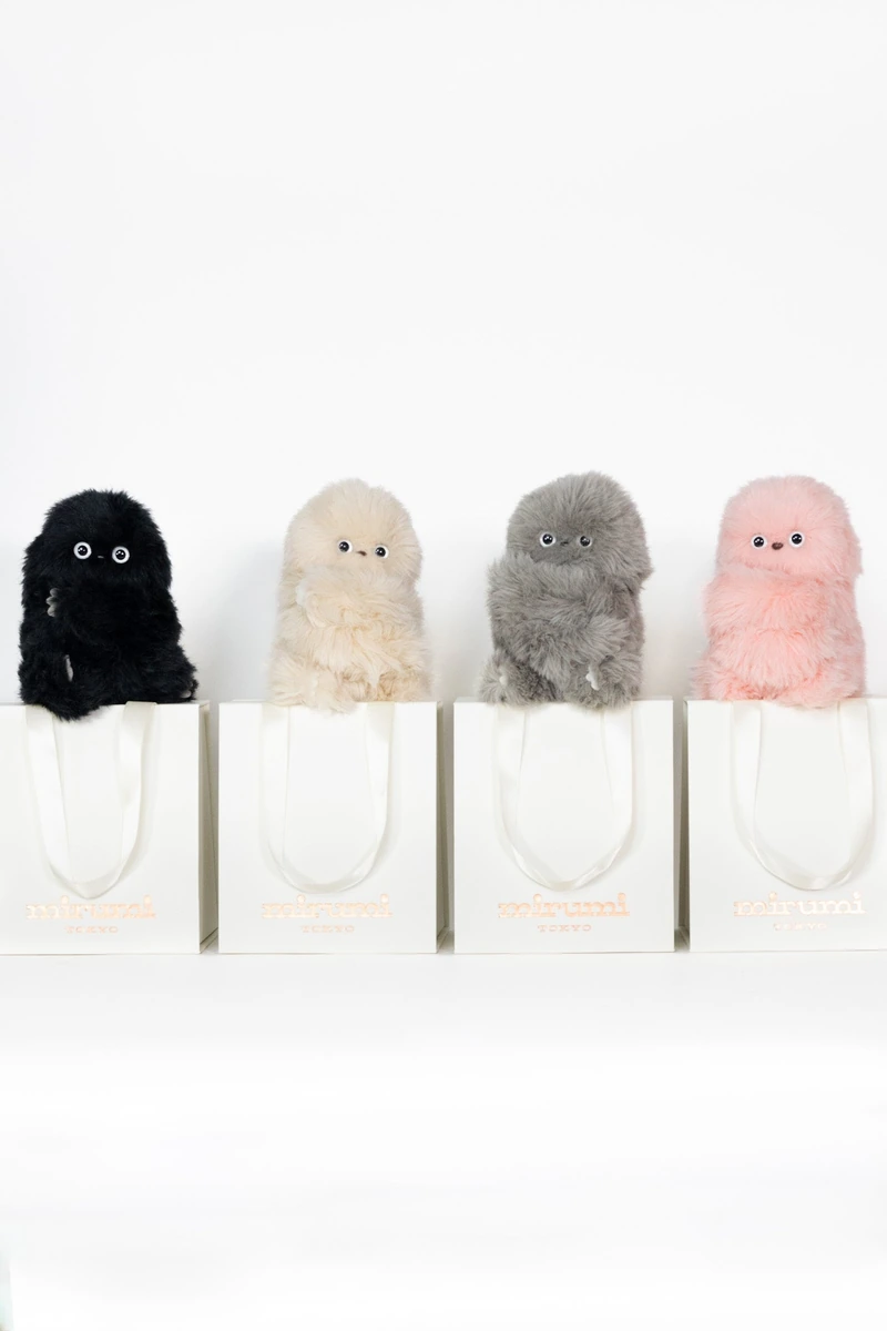 Four mirumi robots in Black, Ivory, Gray and Pink, perched on slim stands.